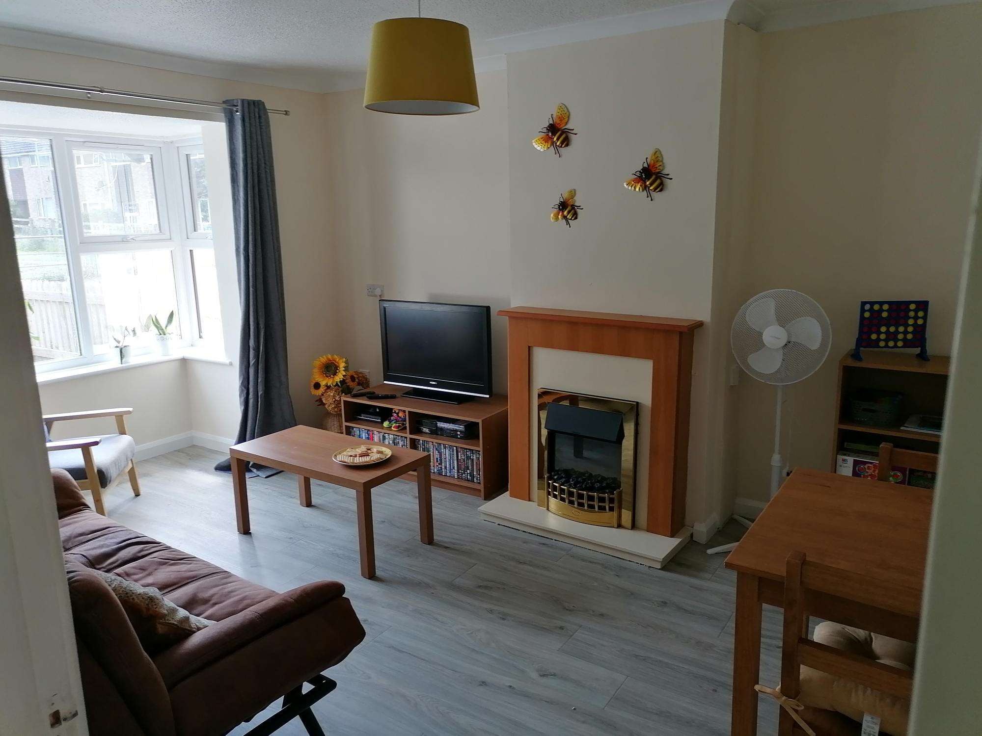 Photograph of the respite bungalow living room with sofa, television and dining table